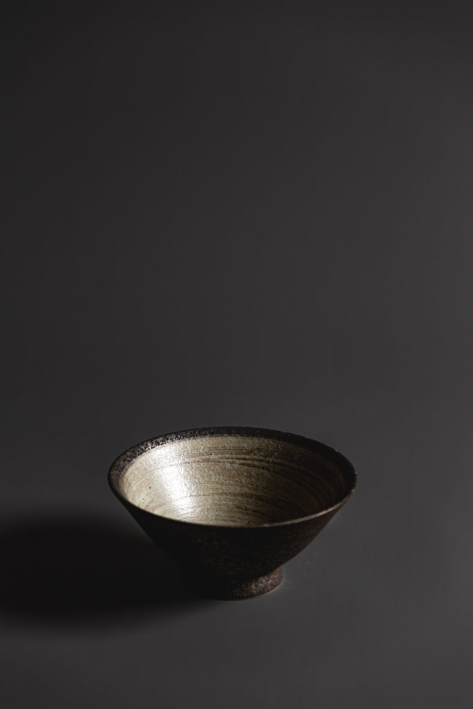 The Nin-Rin range features a circular sweep of golden ochre over the signature 'Earth' glaze. Handmade and so no two pieces are the same.  A natural, beautiful, handcrafted homeware piece that has been ethically sourced. Type: V-Shape Bowl Material: Stoneware Glaze: Nin Rin Dimensions: 155 x70mm